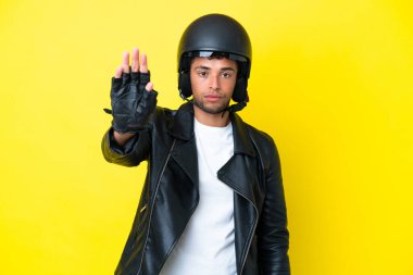 Motosiklet kasklı genç Brezilyalı adam sarı arka planda izole edilmiş.