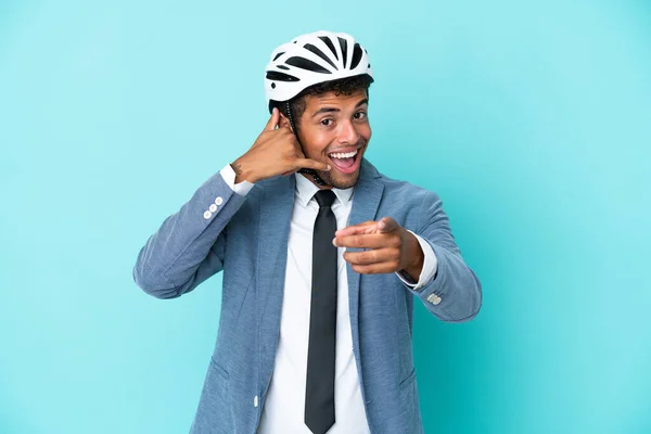 年轻的巴西商人 戴着自行车头盔 与蓝色背景隔离 做着电话手势 指着前方 — 图库照片
