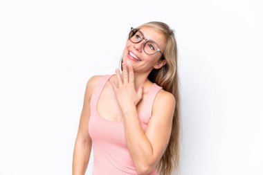 Beyaz arka planda izole edilmiş genç beyaz kadın gülümserken yukarı bakıyor.