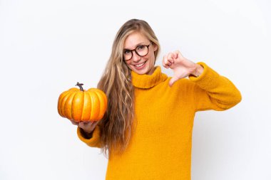 Beyaz arka planda soyutlanmış kabak tutan genç sarışın kadın gururlu ve kendini beğenmiş.