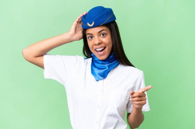 Uçak hostesi Afro-Amerikan kadın izole edilmiş arka planda şaşkın şaşkın ve bir tarafı işaret ediyor.