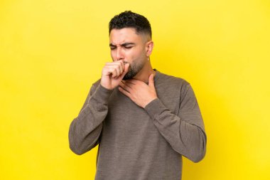 Genç Arap yakışıklı adam sarı arka planda çok öksürüyor.