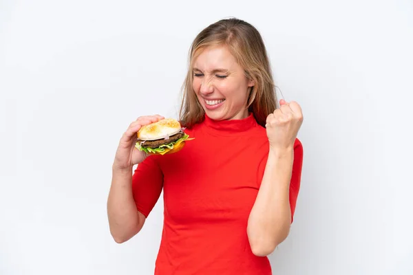 Młoda Blondynka Trzyma Hamburgera Białym Tle Świętując Zwycięstwo — Zdjęcie stockowe