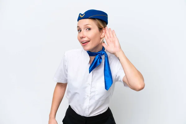 耳に手を置くことによって何かを聞いて白い背景に隔離された飛行機ブロンドスチュワーデス女性 — ストック写真