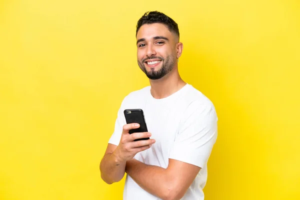 Joven Hombre Árabe Guapo Aislado Sobre Fondo Amarillo Sosteniendo Teléfono —  Fotos de Stock