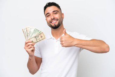 Genç Arap bir adam beyaz arka planda izole edilmiş bir sürü para alıyor ve iyi niyet gösterisi yapıyor.