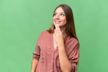 Genç, güzel, sarışın bir kadın, soyutlanmış arka planda gülümserken yukarı bakıyor.