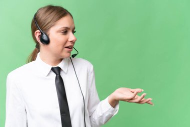 Tele pazarlamacı beyaz kadın, izole edilmiş bir geçmişi olan, şaşırtıcı bir yüz ifadesi olan bir kulaklıkla çalışıyor.