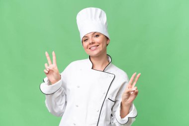 Genç aşçı kadın izole edilmiş yeşil arka plan 