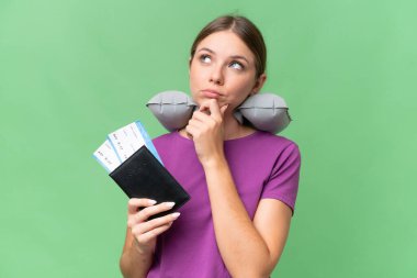 Şişirilebilir seyahat yastığı olan genç, güzel sarışın kadın izole edilmiş arka planda ve yukarı bakıyor.