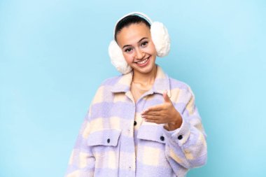 Mavi arka planda izole edilmiş kışlık kuklalar takan genç bir Arap kadın iyi bir anlaşma için el sıkışıyor.