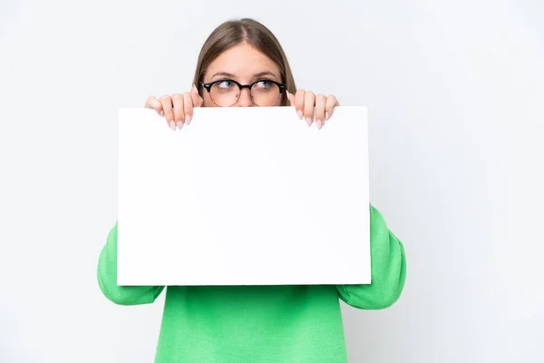 Mladá Běloška Izolovaná Bílém Pozadí Drží Prázdný Plakát Schovává Ním — Stock fotografie