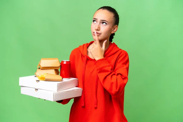 Young Arab Woman Holding Fast Food Isolated Background Having Doubts — Stock Photo, Image