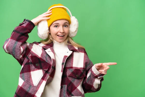 Young English Woman Wearing Winter Muffs Isolated Background Surprised Pointing — Stock Photo, Image