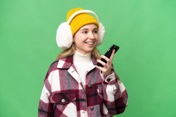 Молодая Англичанка Зимних Муфтах Изолированном Фоне Поддерживает Разговор Мобильным Телефоном — стоковое фото