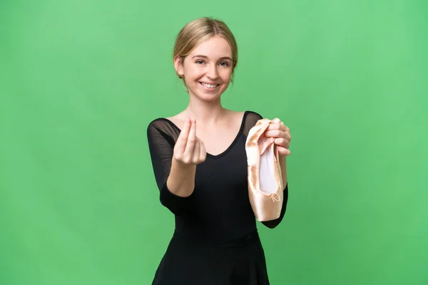 Young English woman practicing ballet over isolated background making money gesture