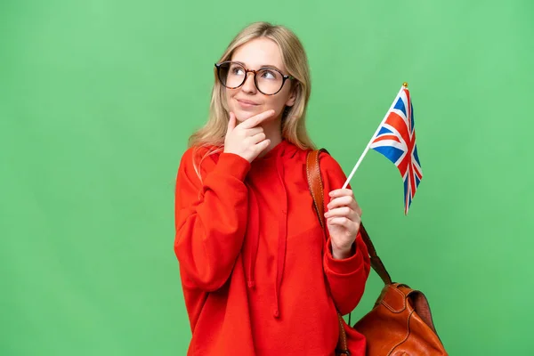 年轻的惊慌失措的女人举着英国国旗 在孤独的背景下抬起头微笑着 — 图库照片