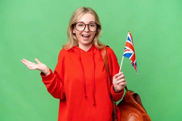 年轻的惊慌失措的女人举着英国国旗 在与世隔绝的背景下带着震惊的表情 — 图库照片