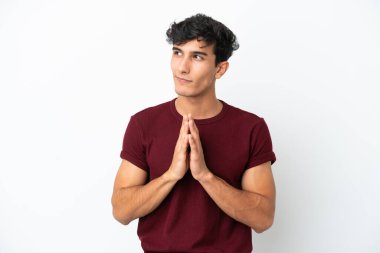 Genç Arjantinli adam beyaz arka planda bir şeyler planlıyor.