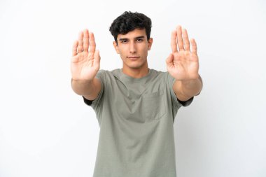 Beyaz arka planda izole edilmiş genç Arjantinli adam durdurma hareketi yapıyor ve hayal kırıklığına uğruyor