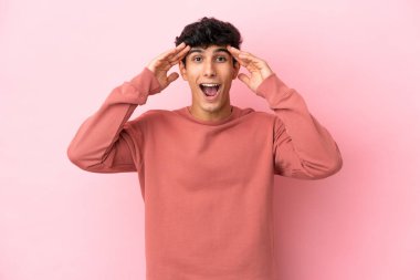 Arjantinli genç bir adam pembe arka planda izole edilmiş, sürpriz bir ifadeyle.