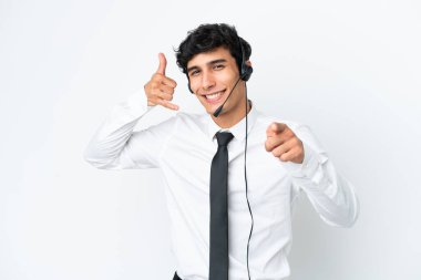 Tele pazarlamacı beyaz arka planda izole edilmiş bir kulaklıkla çalışıyor. Telefon hareketi yapıyor ve ön tarafı işaret ediyor.