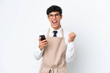 Arjantinli restoran garsonu beyaz arka planda izole edilmiş ve telefon zafer pozisyonunda.