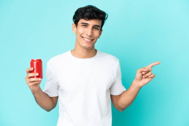 Arjantinli genç adam mavi arka planda izole edilmiş bir içecek tutuyor.