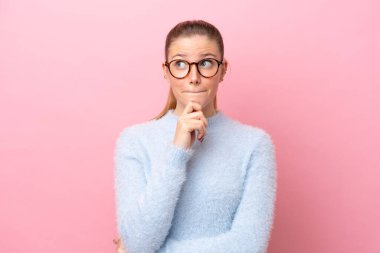 Pembe arka planda soyutlanmış beyaz bir kadın. Şüpheleri ve düşünceleri var.