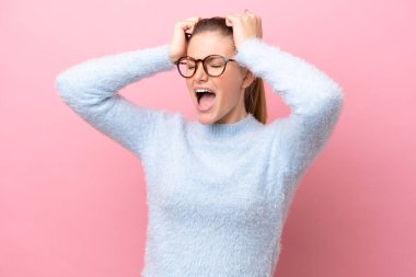 Pembe arka planda izole edilmiş genç beyaz kadın bunalıma girdi.