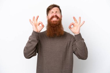 Sakallı kızıl saçlı adam, beyaz arka planda zen pozunda izole edilmiş.