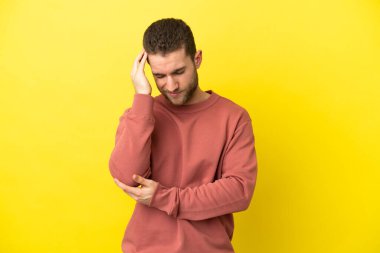 Sarışın yakışıklı, soyutlanmış, sarı arka planlı, baş ağrısı olan bir adam.