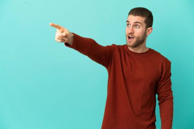 Soyutlanmış mavi arka planda yakışıklı sarışın bir adam.