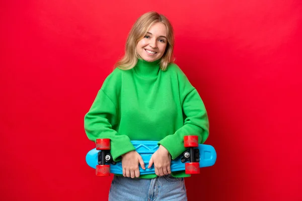 若い英語の女性は幸せな表情でスケートで赤の背景に隔離されました — ストック写真