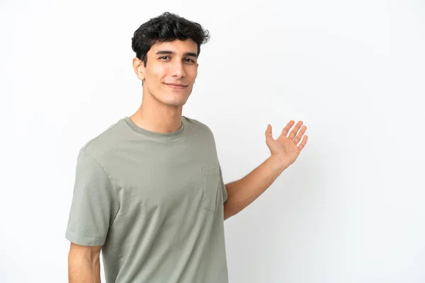 Молодой Аргентинский Мужчина Изолирован Белом Фоне Протягивая Руки Сторону Приглашения — стоковое фото