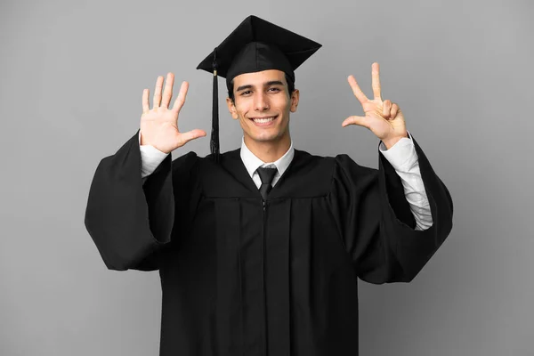 若いアルゼンチンの大学の卒業生は指で8を数える灰色の背景に隔離されました — ストック写真