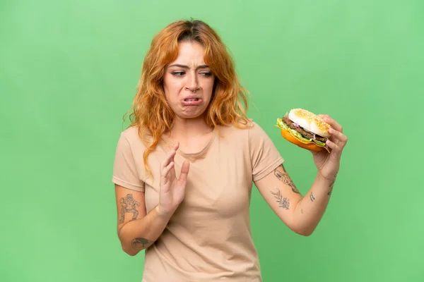 緑の画面に隔離されたハンバーガーを保持若い白人女性クロマキー背景 — ストック写真