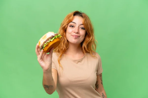 Młoda Kaukaska Kobieta Gospodarstwa Hamburgera Izolowane Zielony Ekran Chroma Klucz — Zdjęcie stockowe