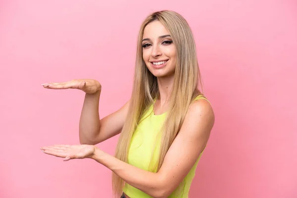 stock image Pretty blonde woman isolated on pink background holding copyspace to insert an ad