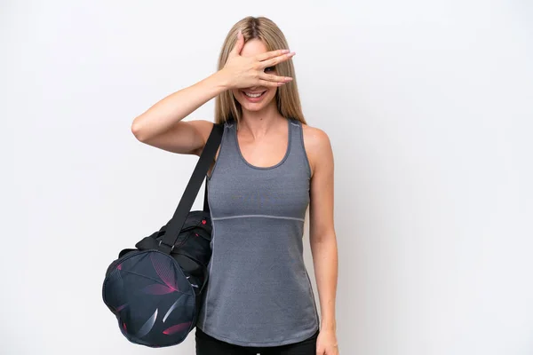 白い背景に手で目を覆い笑顔で孤立したスポーツバッグを持つ若いスポーツ女性 — ストック写真