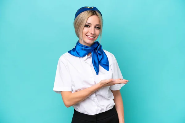 飛行機ブロンドスチュワーデス女性孤立した上に青の背景を提示しながらアイデアを笑顔 — ストック写真