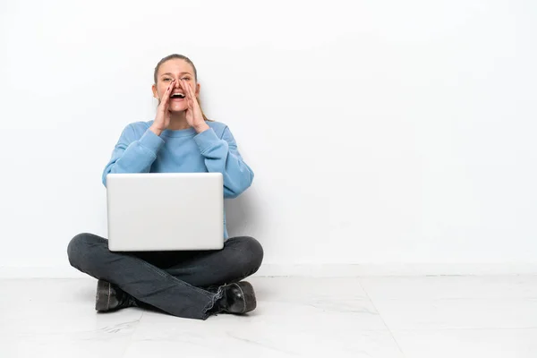 stock image Young woman with a laptop sitting on the floor shouting and announcing something