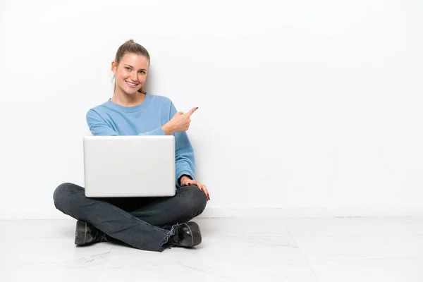 一个拿着笔记本电脑坐在地板上指指点点的年轻女人 — 图库照片
