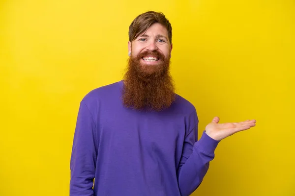 stock image Redhead man with beard isolated on yellow background presenting an idea while looking smiling towards