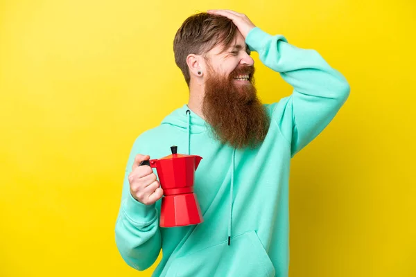 Redhead man with beard holding coffee pot isolated on yellow background has realized something and intending the solution