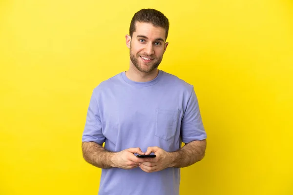 Hezké Blondýny Muž Přes Izolované Žluté Pozadí Posílání Zprávy Mobilním — Stock fotografie