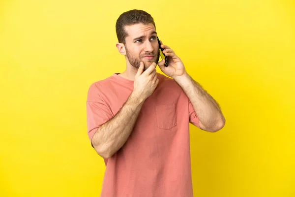 Handsome Blonde Man Using Mobile Phone Isolated Background Having Doubts — Zdjęcie stockowe