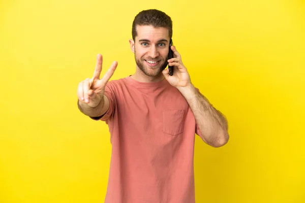 Przystojny Blondynka Człowiek Pomocą Telefonu Komórkowego Odosobnionym Tle Uśmiechając Się — Zdjęcie stockowe