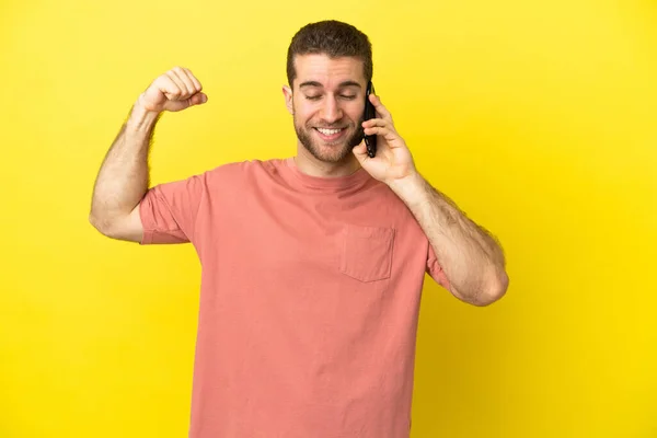 Handsome Blonde Man Using Mobile Phone Isolated Background Doing Strong — Stock Photo, Image