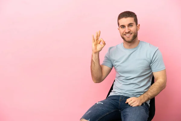 Young Man Sitting Chair Isolated Pink Background Showing Sign Fingers — Stock fotografie
